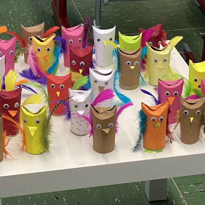Viele bunte Eulen aus Klopapierrollen auf einem Tisch